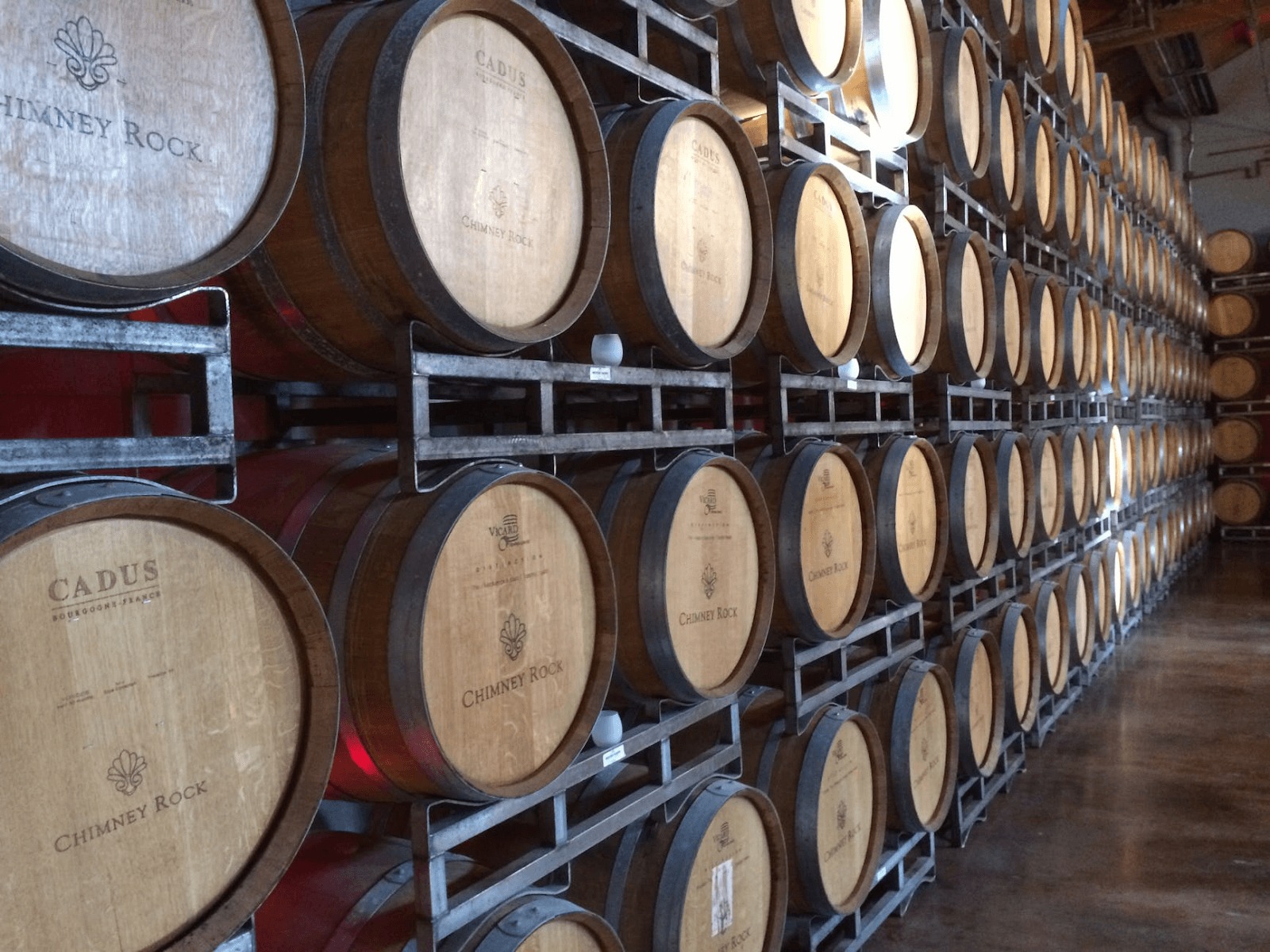 Fileiras de barris de carvalho armazenados em uma adega de vinho.