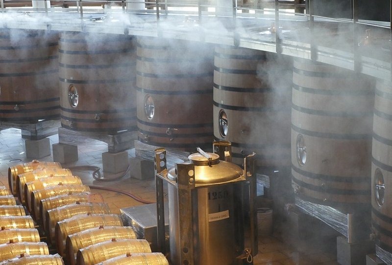 Tanques industriais de vinho em um ambiente cheio de vapor.